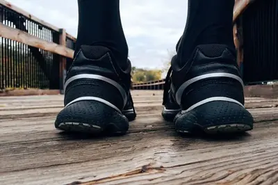 Fötter i svarta sneakers på en träbro